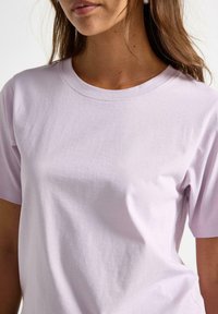Lyse lilla bomulds t-shirt med klassisk crew neck og korte ærmer. Glat tekstur, minimalistisk design og ingen synlige logoer eller mønstre.