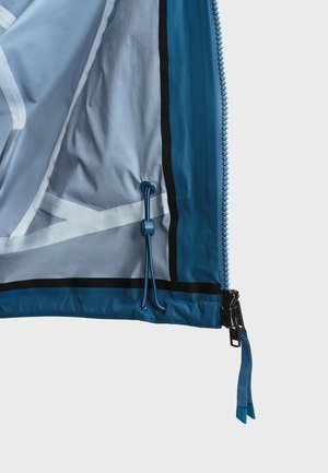 Blauwe jaszoom met rits en trekker en verstelbare koordsluiting aan de binnenkant van de zoom tegen een effen achtergrond.