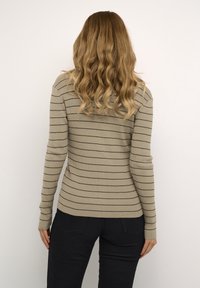 Beige ribbed sweater with dark stripes, long sleeves, and a fitted design. The back features a rounded neckline and a smooth texture.
