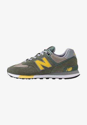 Baskets New Balance vertes et grises avec logo jaune, lacets gris, tissu en mesh, détails en daim, semelle blanche et noire avec accent jaune.