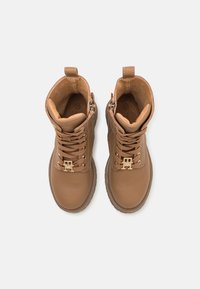 Brune lær ankle boots med guld hardware, rund tå og snørelukning. Glat tekstur med polstret krave og inderside.