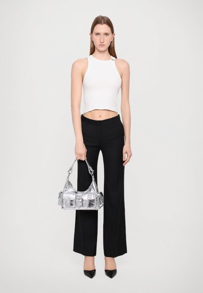 Witte crop top, zwarte wijde broek en glanzende zilveren handtas. Puntige zwarte hakken. Eenvoudig ontwerp met een gladde textuur en minimale details.
