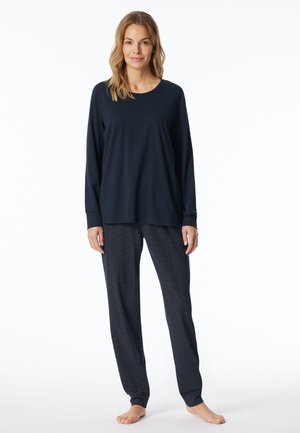 Marinebluse mit Rundhalsausschnitt und langen Ärmeln, kombiniert mit lockeren, gemusterten Hosen mit geometrischem Design und elastischen Bündchen.
