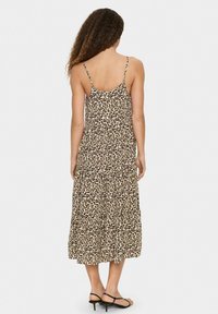 Leopardmönstrad sommarklänning med tunna axelremmar, flödande design, längd till mitten av vadbenet och rynkig textur, med en flerlagerskjol och utskärning på baksidan.