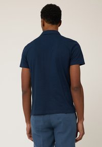 Navyblaues Poloshirt mit kurzen Ärmeln, klassischem Kragen, glatter Textur und geradem Schnitt. Keine sichtbaren Muster oder Akzente.