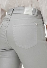 Graue Denim-Hosen mit einer glatten Textur, klassischer Form und Gesäßtaschen mit dezenten Steppdetails. Mit einem silbernen Taillenlabel.