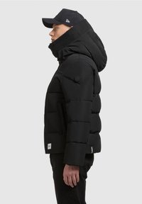 Chaqueta de plumas negra con un alto cuello y capucha, que incluye secciones acolchadas, bolsillos laterales y un parche con el logo en la manga.
