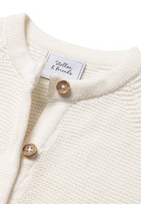 Cardigan color crema realizzato in tessuto a maglia testurizzata, con colletto arrotondato, bottoni in legno e un'etichetta cucita all'interno.