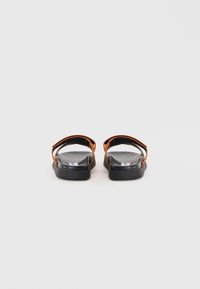 Black sandals with orange straps, featuring a flat sole, transparent upper, and minimalist design. Suitable for casual wear.