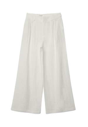 Leveälahkeiset valkoiset pellavahousut, joissa korkea vyötärö, etummaiset laskokset ja vyönlenkit yksivärisellä taustalla.