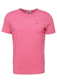 Světle růžové tričko s krátkým rukávem vyrobené z měkké tkaniny, s kulatým výstřihem a malou logem na levé hrudi.