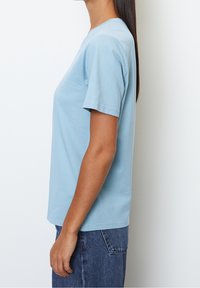Light blue, short-sleeve t-shirt made of soft fabric, featuring a classic crew neck design and a straight cut. Worn with denim jeans.