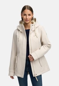 Vaalea beige huppari, jossa on vetoketjusuljenta, sivutaskut ja ribbireunat. Varustettu pehmeällä sisävuorella ja hienovaraisella brändäysdetaililla.