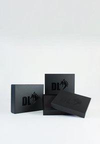 Des boîtes noires avec un fini mat, présentant un logo "DL" en relief et un design de cheval. Trois boîtes de tailles et profondeurs variées.