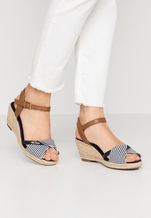 Sandales compensées en espadrille avec des brides en faux cuir marron et un dessus en tissu rayé bleu marine et blanc. Talon compensé enveloppé de corde naturelle.