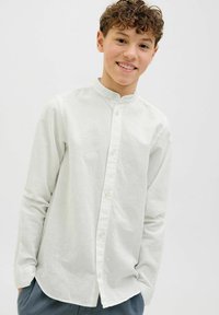 Camicia a maniche lunghe, con bottoni, in tessuto grigio chiaro con colletto alla cinese e una leggera texture. Presenta bottoni lungo la parte anteriore e orlo curvo.