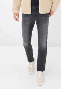 Jeans grigio scuro con taglio dritto, realizzati in denim. Presentano leggero scolorimento e tasche frontali, abbinati a sneakers chiare.