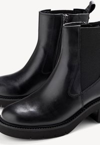 Black leather ankle boots with elastic side panels, smooth texture, zip closure, and a chunky rubber sole. Classic and versatile design.