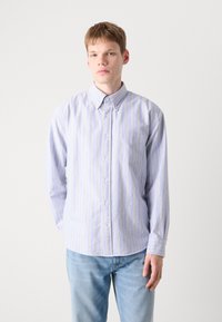 Ριγέ πουκάμισο με κουμπάκια σε ανοιχτό μπλε και κίτρινο, με καπάκι γιακά και μία τσέπη στο στήθος. Μαλακό ύφασμα με χαλαρή εφαρμογή.