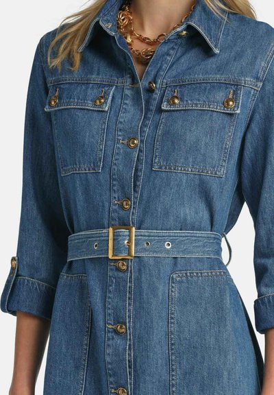 Denimskjortekjole i mellemblå med lange ærmer, to forlommer, guldknapper og et matchende bælte med guldspænde.