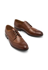 Braune Leder-Dressschuhe mit Wingtips-Design, ausgestattet mit durchbrochenen Details, Schnürverschluss und glatter Oberfläche. Klassische, abgerundete Schuhspitze.