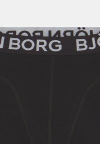 Svarte undertøy med bred elastisk midje med "BJÖRG" i kontrasterende hvite bokstaver; glatt tekstur og tettsittende design.