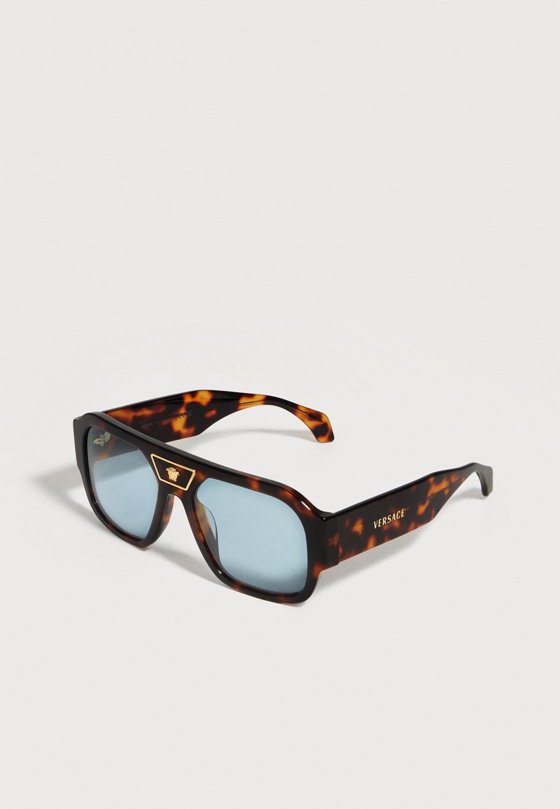 Ορθογώνια γυαλιά ηλίου με φίλτρο χελώνας και μπλε φακούς, με χρυσό λογότυπο Versace στα μπράτσα και το έμβλημα της Μέδουσας στη γέφυρα.