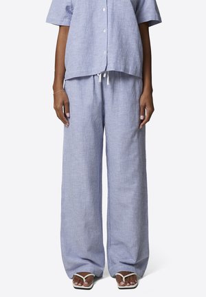 Persona che indossa pantaloni larghi a righe larghe blu chiaro e bianche con coulisse in vita e camicia a maniche corte abbottonata abbinata, sandali bianchi.