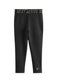 Zwarte sportleggingen met een brede, gemusterde tailleband met de tekst "NEXT ACTIVE" en een klein logo op het onderbeen aan de linkerkant. Glad, rekbaar materiaal.