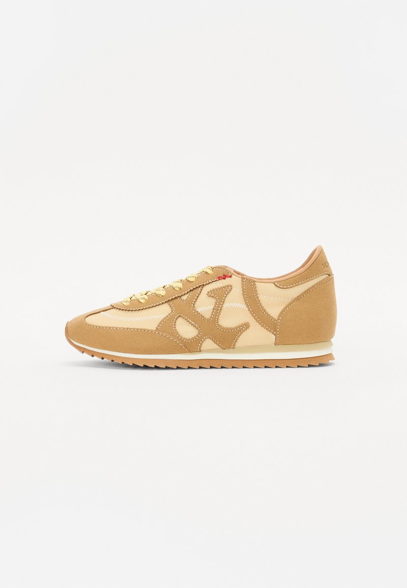 Brune semsket lær og lærsneaker med hvite detaljer, snøring, teksturerte paneler og en gummisåle med et sikksak-mønster.