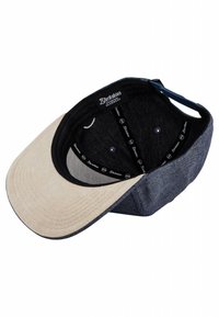Gorra bicolor que presenta un visera beige y una corona de tela azul oscuro. El interior tiene un forro negro con el logotipo y seis orificios de ventilación.