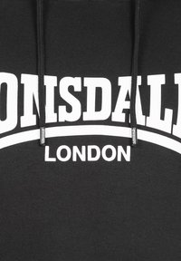 Fekete kapucnis pulóver, amelyen merész fehér szöveg olvasható: "LONSDALE" és "LONDON", ívelt díszítésekkel. Az anyag lágy érzetű, és jól látható fűzők találhatók rajta.