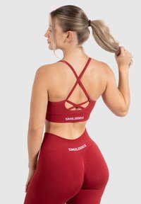 Rode sportbeha met kruislingse banden, logo op de band, gecombineerd met hoge taille legging met een vergelijkbaar logo en textuuraccenten.
