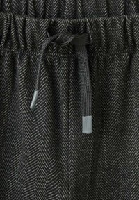 Čierna tkanina so vzorom rybej kosti s jemným leskom, obsahujúca naťahovaciu pásovku a nastaviteľné šnúrky so sivými koncami.