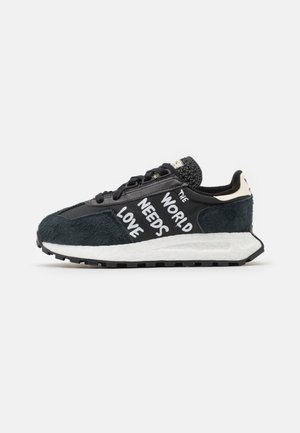 Czarny i ciemnoszary sneaker z białą podeszwą i napisem „ŚWIAT POTRZEBUJE MIŁOŚCI” napisanym na białym bocznym panelu.