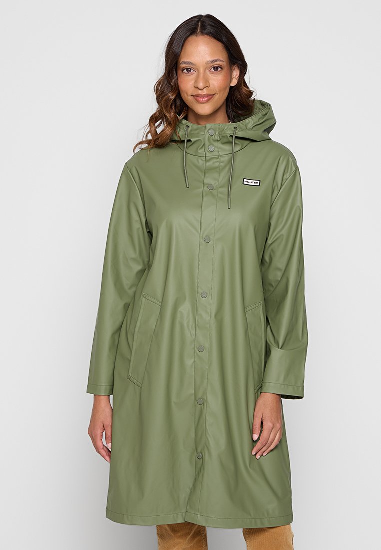 Green waterproof raincoat made of smooth material, featuring a hood, snap buttons, two side pockets, and a brand label on the chest.