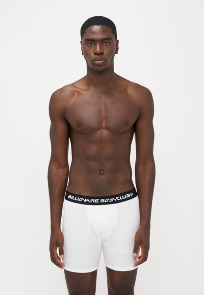 Boxers brancos com uma cinta preta apresentando o texto "Billionaire Boy Club". O tecido é suave e ajustado ao corpo.