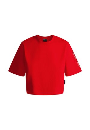 T-shirt court à manches courtes en coton rouge avec une coupe boxy. Présente le texte "RED BULL RACING" sur la manche gauche et une étiquette sur le côté inférieur.