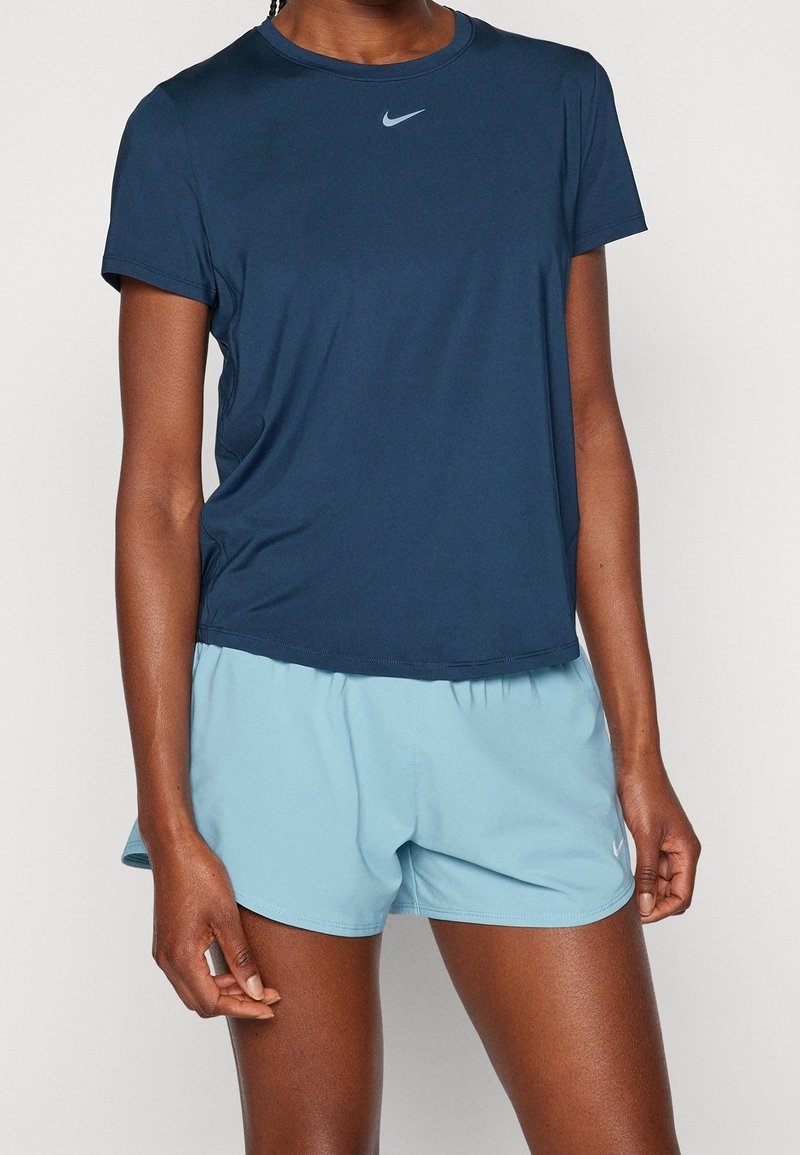 Camiseta atlética de color azul marino con mangas cortas y cuello redondo, combinada con pantalones cortos de color azul claro. Presenta un pequeño logo de Nike en el pecho.