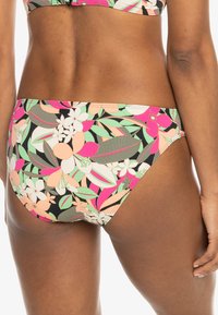 Bas de bikini avec un motif floral en rose, vert et blanc sur fond noir; fait en tissu lisse avec une taille mi-haute.