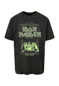 Svart bomull t-shirt med en grön grafisk tryck med text och en illustration relaterad till Iron Maidens turné i Japan 1985.