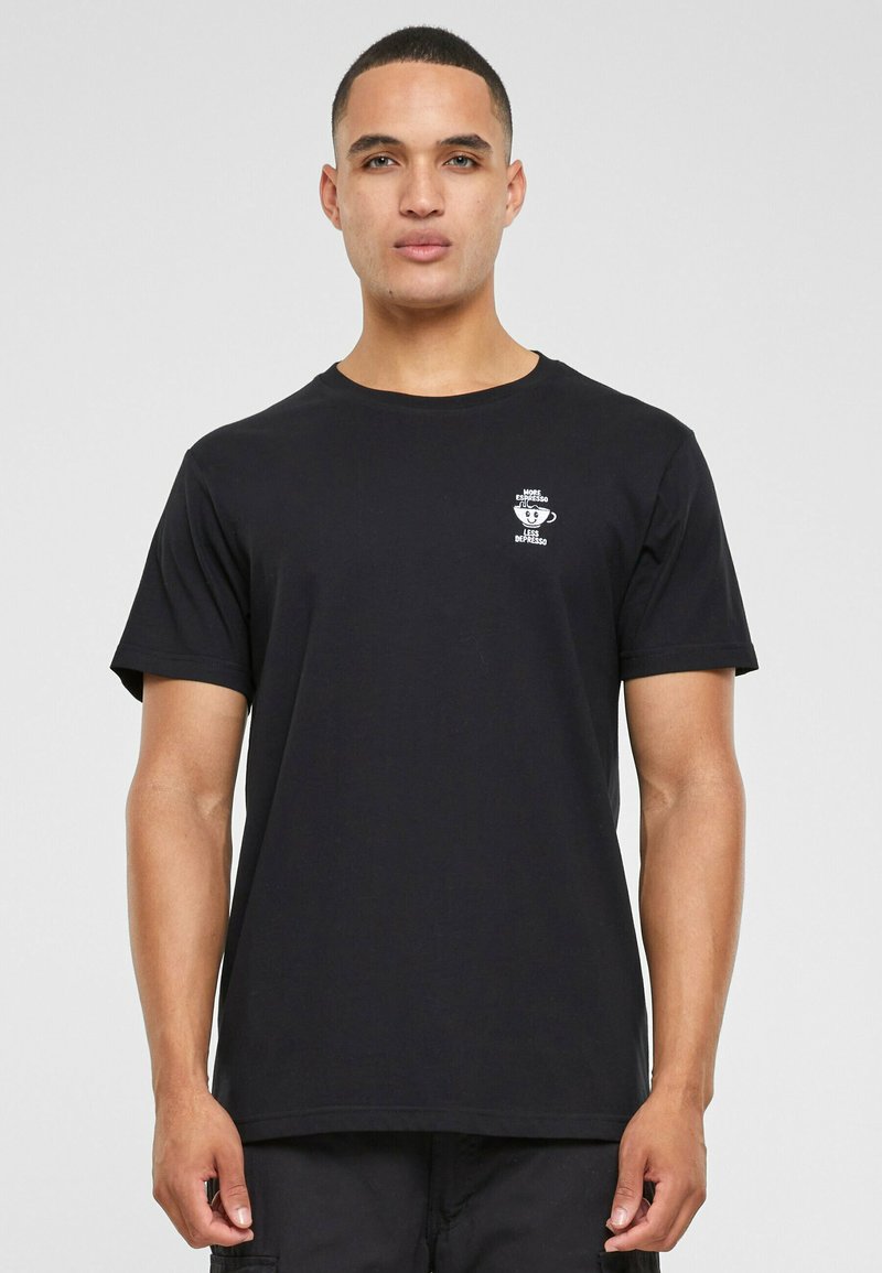 Sort bomulds T-shirt med korte ærmer. Har et lille hvidt grafisk print på brystet. Klassisk rund halsudskæring. Løs pasform.