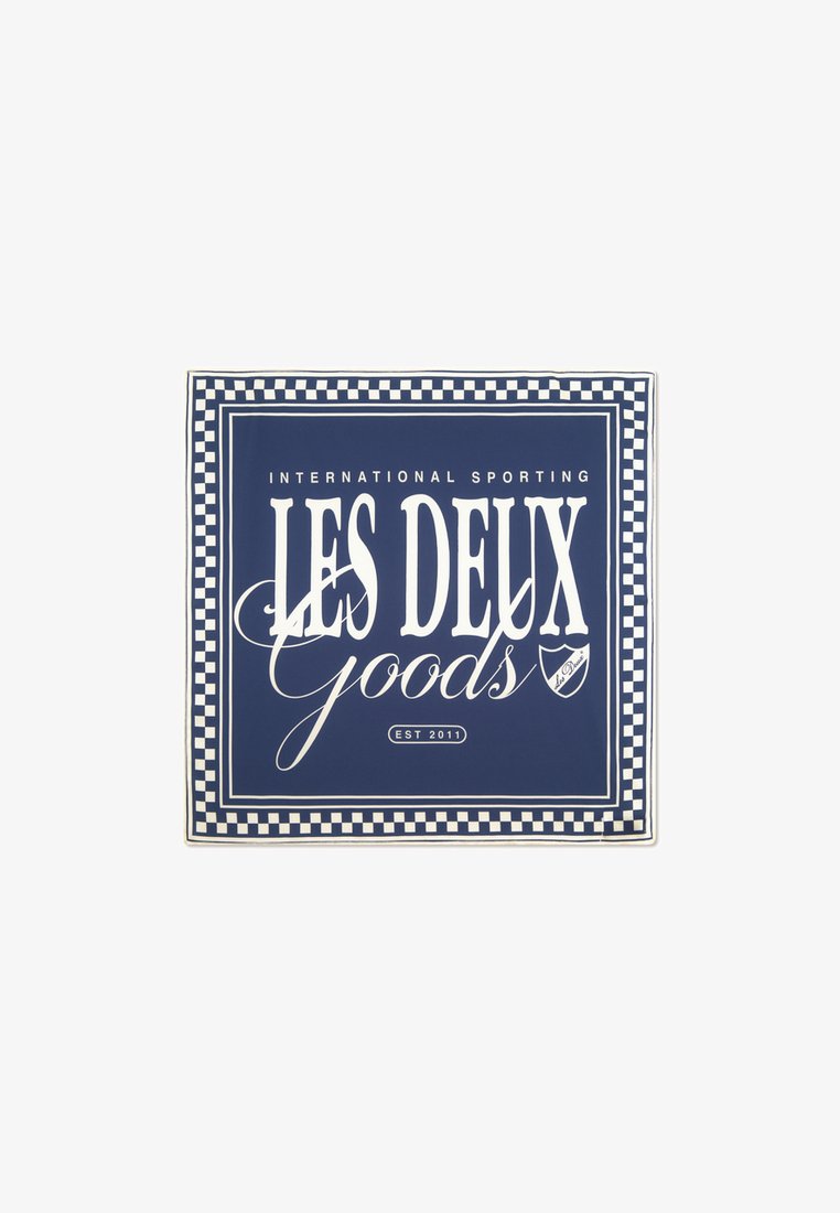 Etichetă rectangulară marină cu text alb "LES DEUX Goods" și "INTERNATIONAL SPORTING" deasupra, având un contur în carouri. Înființată în 2011.