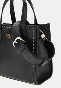 Borsa a mano nera in pelle con hardware dorato, caratterizzata da cuciture beige a contrasto, manici corti e una tracolla removibile.