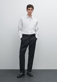 White button-up shirt, black trousers, black shoes. The shirt features long sleeves, and the trousers are tailored with a straight fit.