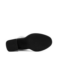 Semelle de chaussure noire en caoutchouc texturé pour une meilleure adhérence, avec un léger talon et une forme lisse et courbée. Aucune marque ou motif visible.