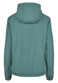 Turkusowa, lekka kurtka z kapturem. Posiada elastyczne mankiety i dół, gładką fakturę oraz minimalistyczny design. Widok z tyłu.