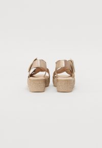 Metallic gold sandals with a textured espadrille wedge sole. Features a narrow strap with a decorative accent. Plain inner lining.