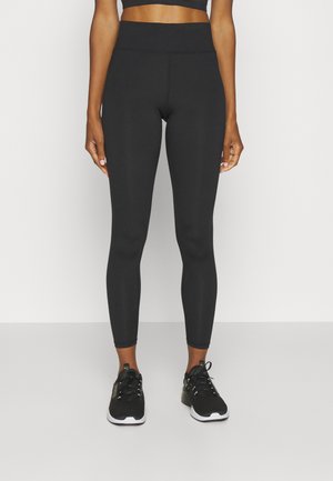 Zwarte leggings van rekbaar materiaal met een hoge taille, een gladde textuur en een slim fit, gecombineerd met zwarte sportschoenen.