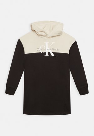 Bluza z kapturem o kremowej górnej części i czarnej dolnej. Posiada duże logo "CK" oraz napis "Calvin Klein Jeans" w kolorze białym.